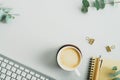 Flat lay top view feminine workspace with coffee cup, keyboard, office supplies, eucalyptus branches on green background. Home Royalty Free Stock Photo