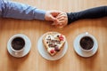 Flat lay, top view of man and woman holding hands while drinking coffee with cream cake Royalty Free Stock Photo