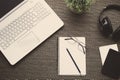 Flat lay. Top view of an office with laptop, notebook, pencil, headphones, glasses, passport, books and plant