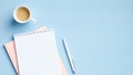 Flat lay, top view office table desk. Workspace with blank paper notepad, cup of coffee and pen on blue background. Feminine Royalty Free Stock Photo