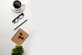 Flat lay, top view office table desk. Workspace with blank, office supplies, pencil, green leaf, and coffee cup on white Royalty Free Stock Photo