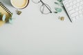 Flat lay, top view office table desk. Workspace with cup of coffee, keyboard, glasses, paper notebook on green background.