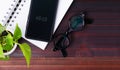 Flat lay, top view office table white desk. Workspace with blank notebook, eyeglasses, green plant, on white background Royalty Free Stock Photo