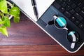 Flat lay, top view office table wooden desk. Workspace with blank laptop, eyeglasses, diary,and green plant on background. Royalty Free Stock Photo