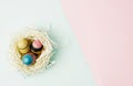 Flat lay top view paper nest with three vintage Easter eggs on blue and pink background Royalty Free Stock Photo
