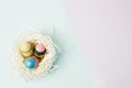 Flat lay top view paper nest with three vintage Easter eggs on blue and violet background Royalty Free Stock Photo