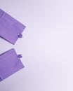 Flat lay top view of purple paper gift bags with little tweezers with hearts on them on the left. Holidays presents and Valentines Royalty Free Stock Photo