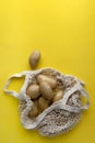 Flat lay top view raw organic potatoes in string bag on yellow background Royalty Free Stock Photo