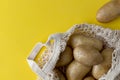 Flat lay top view raw organic potatoes in string bag on yellow background Royalty Free Stock Photo