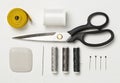 Flat lay top view sewing tools with measurement tape, chalk, thread, needles and scissors on white wood table