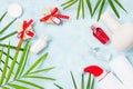 Flat lay top view shampoo bottles with Christmas gifts, soap bar and green palm leaves on blue background. Holiday vacation mockup