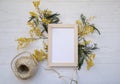 Flat lay top view vintage floral composition, blank photo frame, jute rope spool and mimosa flowers on the light grey background Royalty Free Stock Photo