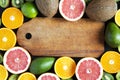 Flat lay. Top view. Wooden board with sliced colorful fresh fruits: kiwi, orange, grapefruit and mandarin.