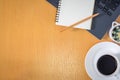 Flat lay, Top view work space in office. with laptop, notebook, pencil, white coffee cup on wooden Table.