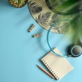 Flat lay, top view workspace with eye glasses, notebook, hat, pencil, green leaf, shoes and coffee cup on blue background. Royalty Free Stock Photo