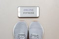 sports at home in quarantine, gray running shoes for running and a smartphone with the inscription onlin Royalty Free Stock Photo