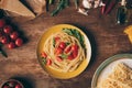 flat lay with traditional italian pasta with tomatoes and arugula in plate on wooden table Royalty Free Stock Photo