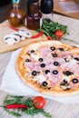 Flat lay with traditional Italian pizza with ham and olives on black stone table and various ingredients Royalty Free Stock Photo