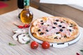 Flat lay with traditional Italian pizza with ham and olives on black stone table and various ingredients Royalty Free Stock Photo