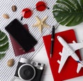 Flat lay travel concept: planner, passport, smartphone, camera, pen, star fish and monstera leaves on wooden background