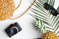 Flat lay traveler accessories with palm leaf on white background. Top view rattan straw bag, vintage camera, sunglasses, pineapple Royalty Free Stock Photo