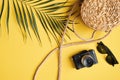 Flat lay traveler accessories on yellow background. Top view palm leaf, rattan straw bag, vintage camera, sunglasses. Travel or Royalty Free Stock Photo