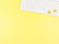 flat lay of two yellow circle smiling faces on white computer keyboard on yellow background Royalty Free Stock Photo