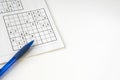 Flat lay unsolved sudoku, blue pen, on white table. Space for text Royalty Free Stock Photo