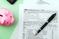 Flat Lay US Tax 1040 Form, pen and piggy bank