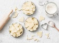 Flat lay Valentine`s day baking background. Raw apple tartlets in the baking dish and baking ingredients on light background