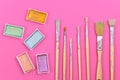 Flat lay with various metallic colorful watercolors and used dirty paint brushes on pink backgrund Royalty Free Stock Photo