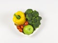 Flat lay of vegetables capsicum, broccoli tomatoes and green apple in heart shape plate on white background with copy space,