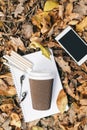 Flat lay view of autumn leaves, tablet, phone and paper cup of coffe. From above with legs