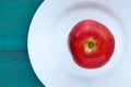 Flat lay view of a fresh red apple served on a white plate