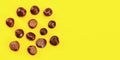 Flat lay view - horse chestnuts scattered on yellow board, space for text on right side. Autumn background