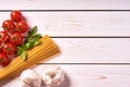 Flat lay view of pasta or spaghetti with bunch of tomatoes, garlic and basil leaves. Old white wooden background or table top Royalty Free Stock Photo