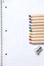 Flat lay view of white notebook , color pencils and pencil sharpener on a table. Preparing for a school. Royalty Free Stock Photo