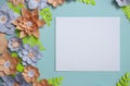 Flat lay of vintage square card frame, color paper flowers design on blue background. Top view, copy space, floral art Royalty Free Stock Photo