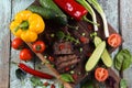 Flat lay of well done steak on oak board served with chili, tomatoes, cucumbers, bell peppers, spring onion and arugula Royalty Free Stock Photo