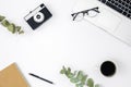 Flat lay white background with laptop, retro camera, coffee cup and glasses.