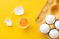 Flat lay of white eggs in the carton brown box on the yellow background. Top view of broken egg with white shell. Copy space for a Royalty Free Stock Photo