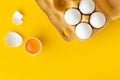 Flat lay of white eggs in the carton brown box on the yellow background. Top view of broken egg with white shell. Copy space for a Royalty Free Stock Photo