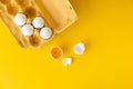 Flat lay of white eggs in the carton brown box on the yellow background. Top view of broken egg with white shell. Copy space for a Royalty Free Stock Photo