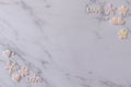 Flat lay of white marble background decorates with shining pink white pearl of hearts, letter of LOVE, snowflakes, and flowers