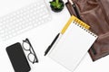 Flat-lay of White office desk table layout. keyboard, glasses, smartphone, notebook and laptop case.