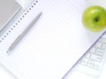 Flat lay white office desktop with blank notebook and pen, green apple put on the keyboard. Royalty Free Stock Photo