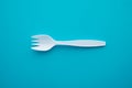 Flat lay of white plastic spork (fork plus spoon) on blue background. Royalty Free Stock Photo