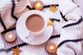 Flat lay. White porcelain cup with coffee with milk, sweater, coarse knitted textile, black and white stripe safe candles, gold st