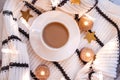 Flat lay. White porcelain cup with coffee with milk, sweater, coarse knitted textile, black and white stripe safe candles, gold st