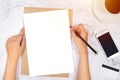 Flat lay of woman hand writing in a blank white paper on brown paper envelope with pencil ,mobile phone , credit card